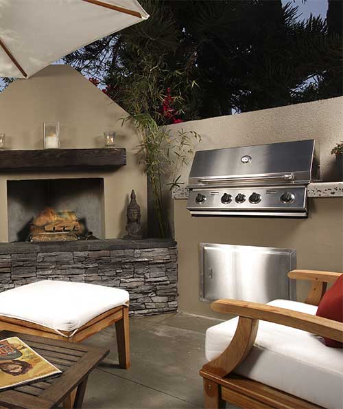 Artisan grill in an outdoor room with beautiful fireplace and furniture.
