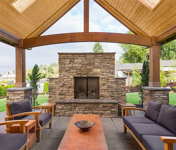beautiful outdoor room with a large stone fireplace and comfy outdoor furniture