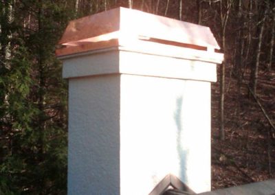 Custom Copper Wind Guard. Chimney is white stucco and there are fall trees in the background.