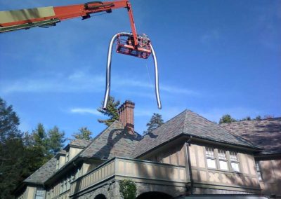 Stainless Steel Liner Installation in Asheville with crane lifting the liner and two men in the bucket. Very elaborate german look to the home.