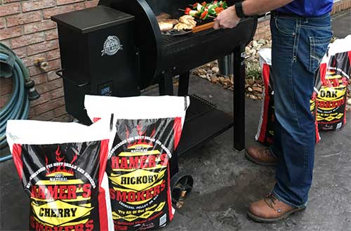 Hamer brand pellet fuel bags and man grilling on an outdoor grill.